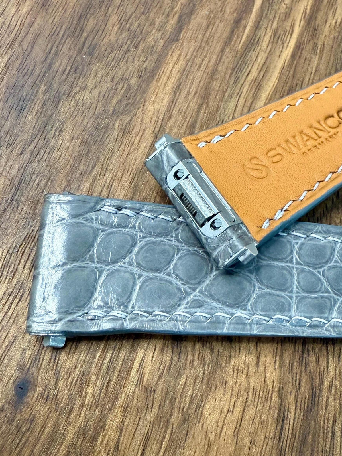 Inside of a handmade alligator watch strap showing the tan leather lining and white hand stitching